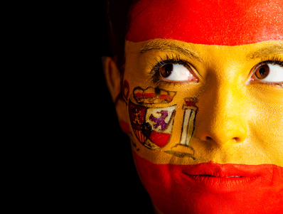 Pensive Spanish woman with the flag painted on her face Ð isolated over a black background